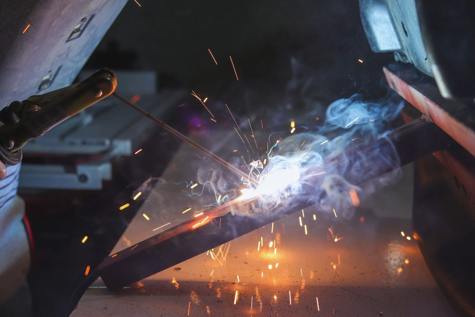 Close view of a weld bead forming on steel with blue arc light and sparks